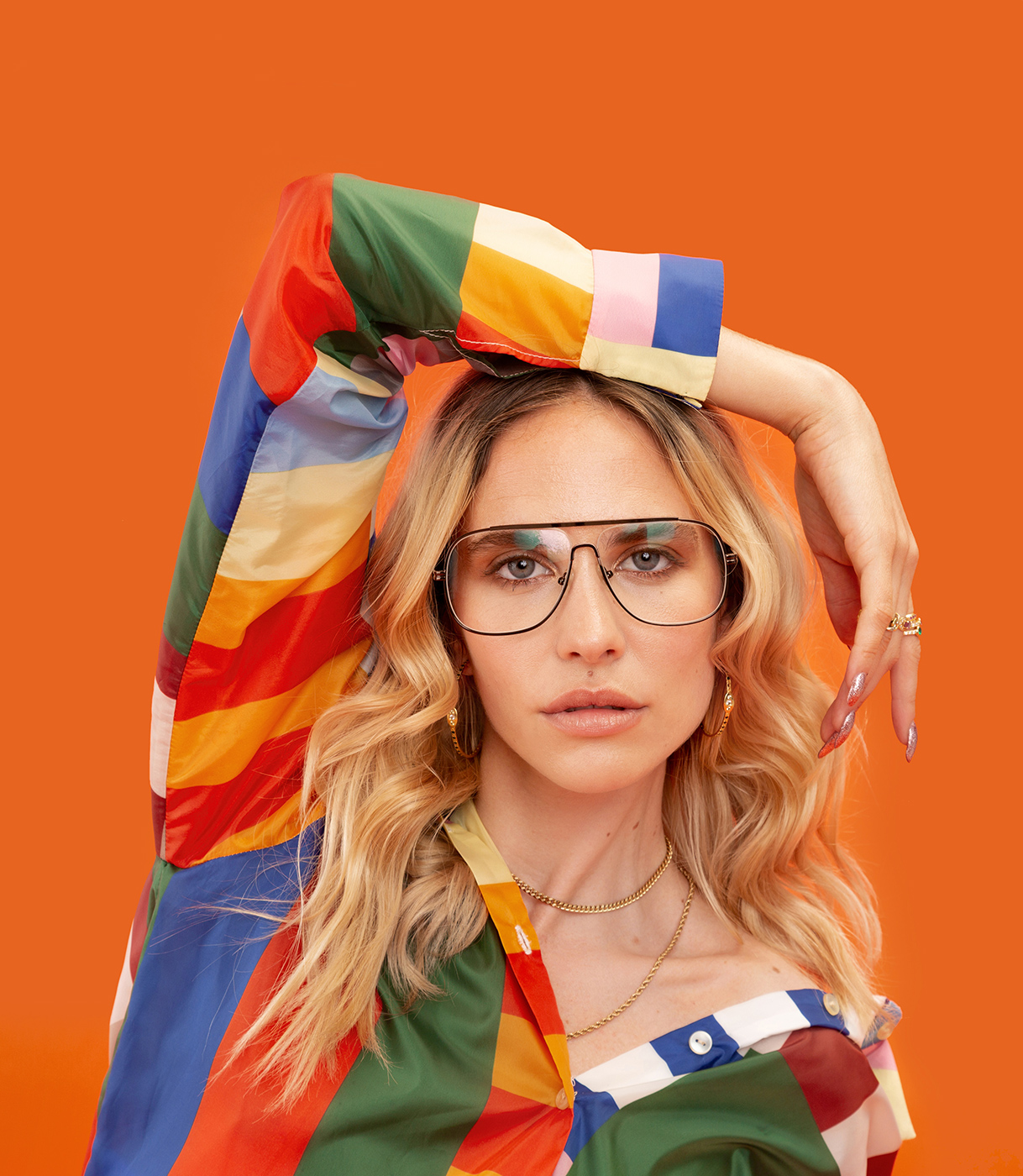Brisa Fenoy con gafas y una camisa de colores geométricos con su brazo derecho sobre su cabeza