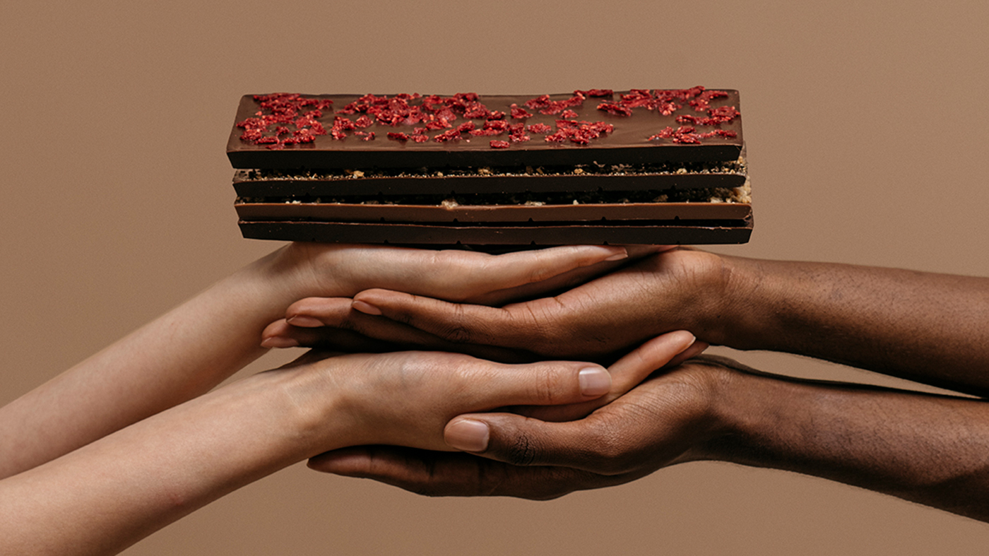 Varias manos juntas sostienen varias tabletas de chocolate abiertas