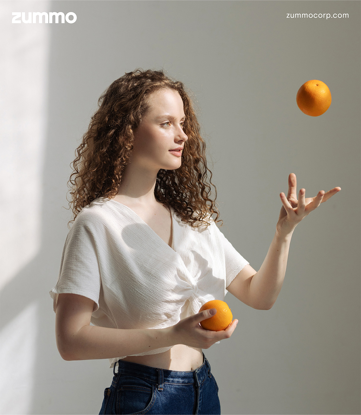 Una joven lanza al aire una naranja mientras con la otra sostiene una segunda naranja