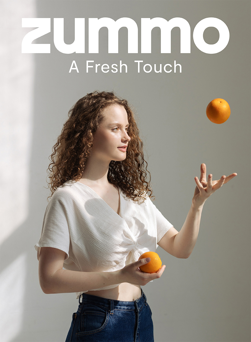 Cartel publicitario de Zummo en el que una joven lanza una naranja al aire al estilo de malabarismos con pelotas