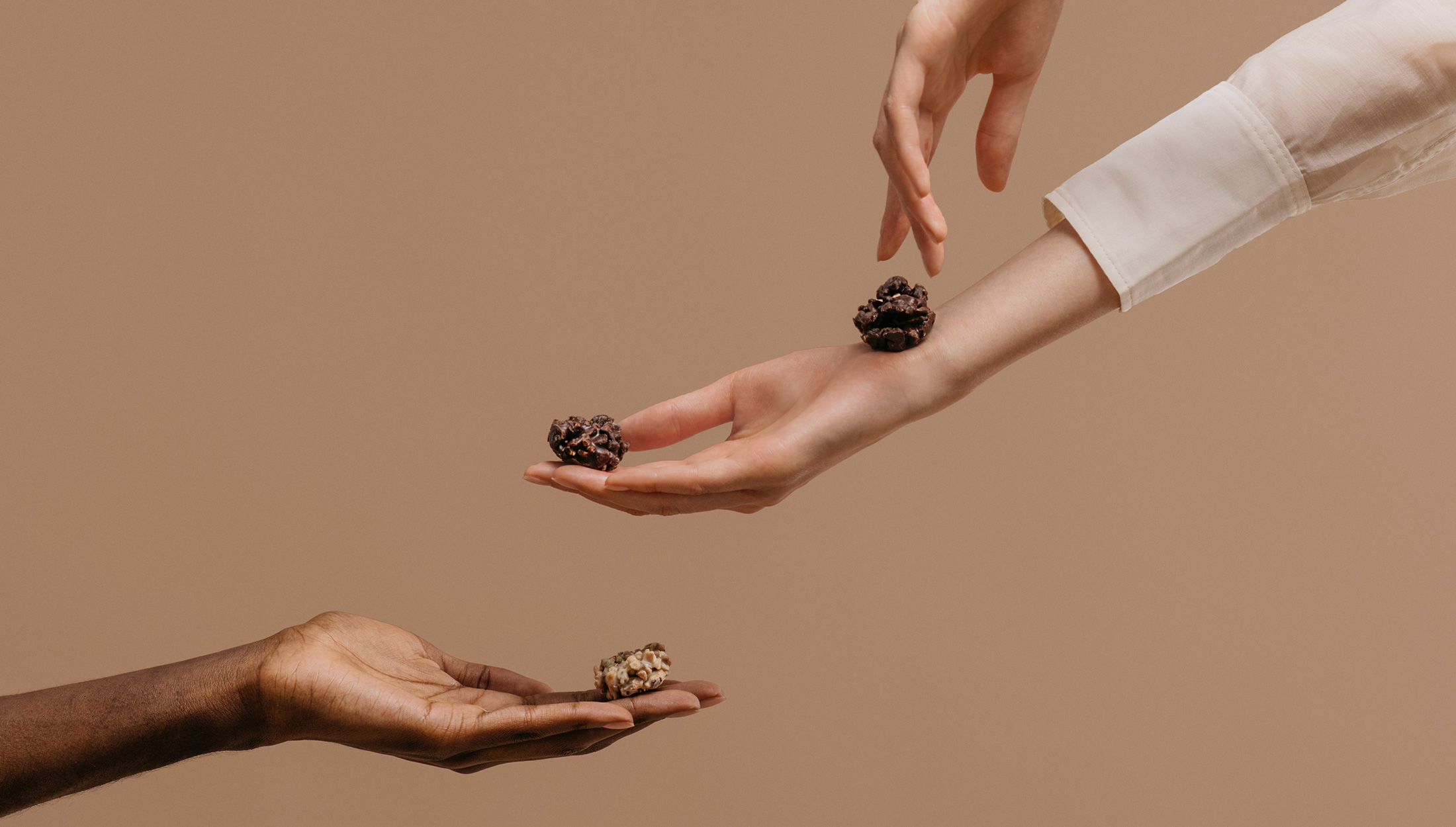 2 manos delicadas de 2 mujeres tienen en sus manos pequeños trozos de chocolate