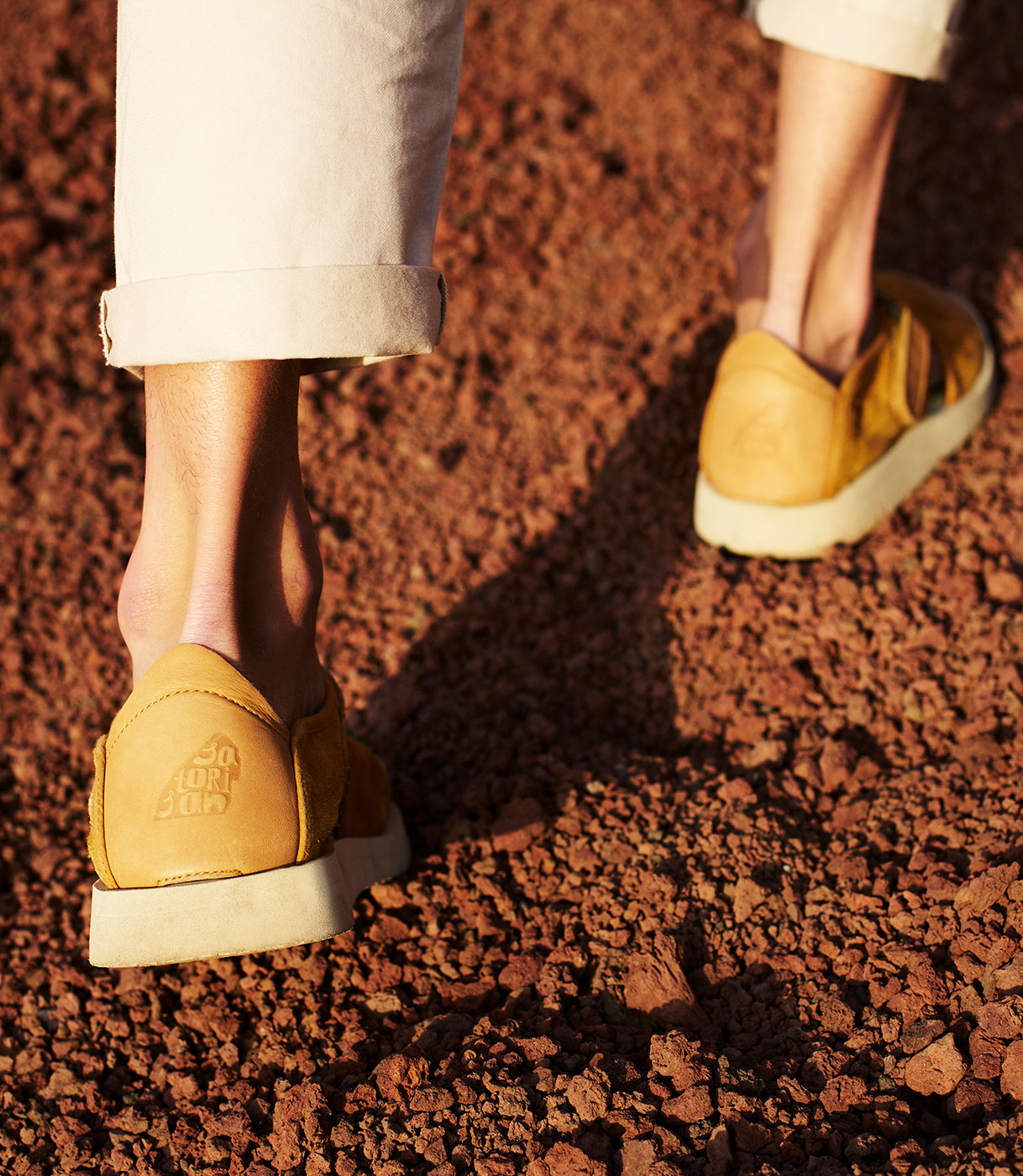 Detalle de los zapatos de Satorisan caminando sobre tierra rojiza