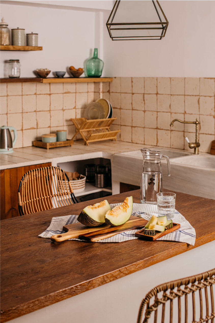 Una cocina doméstica con una mesa de madera y un melón cortado listo para comer