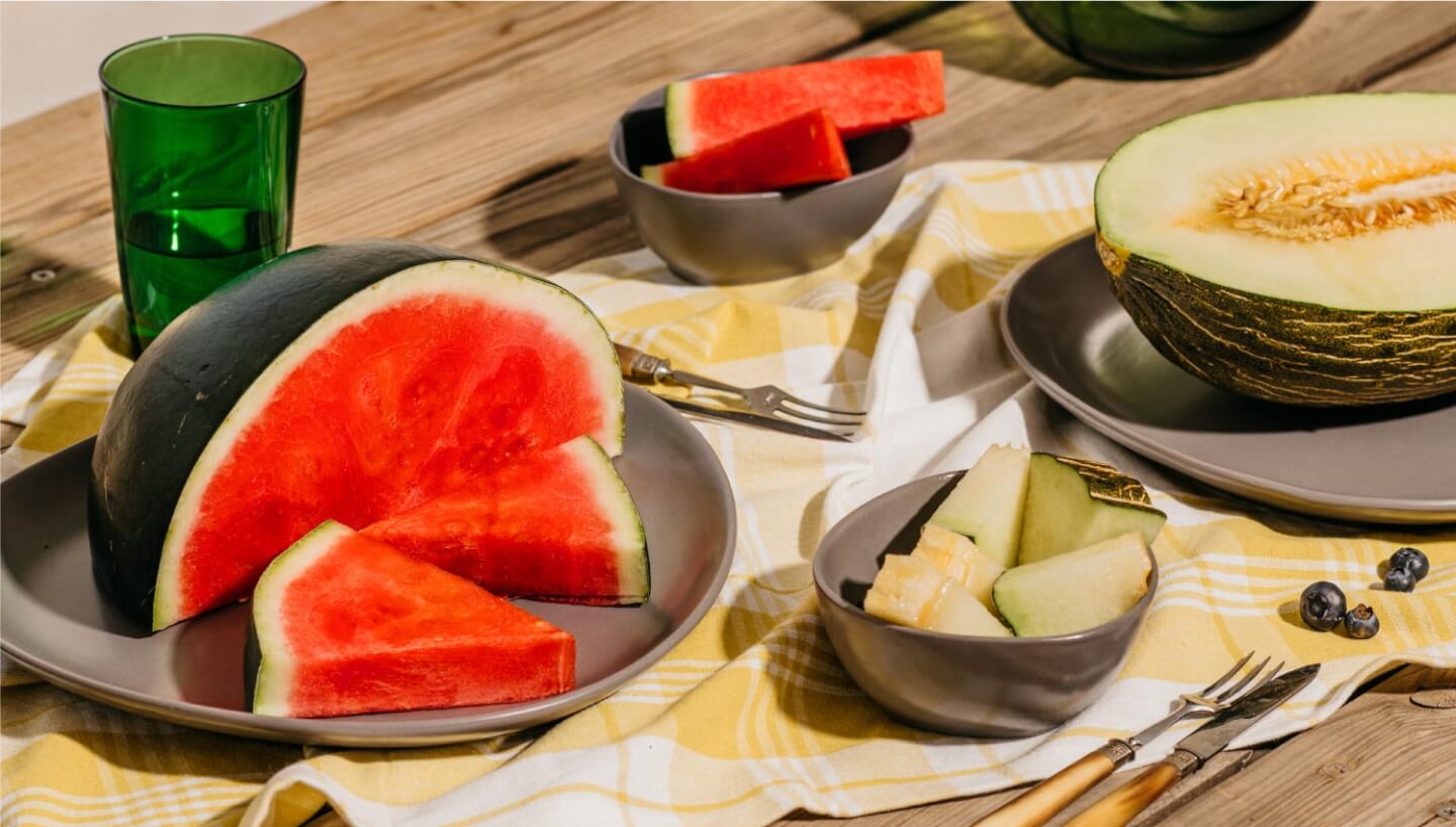 Una mesa al sol con sandías y melones preparados para comer