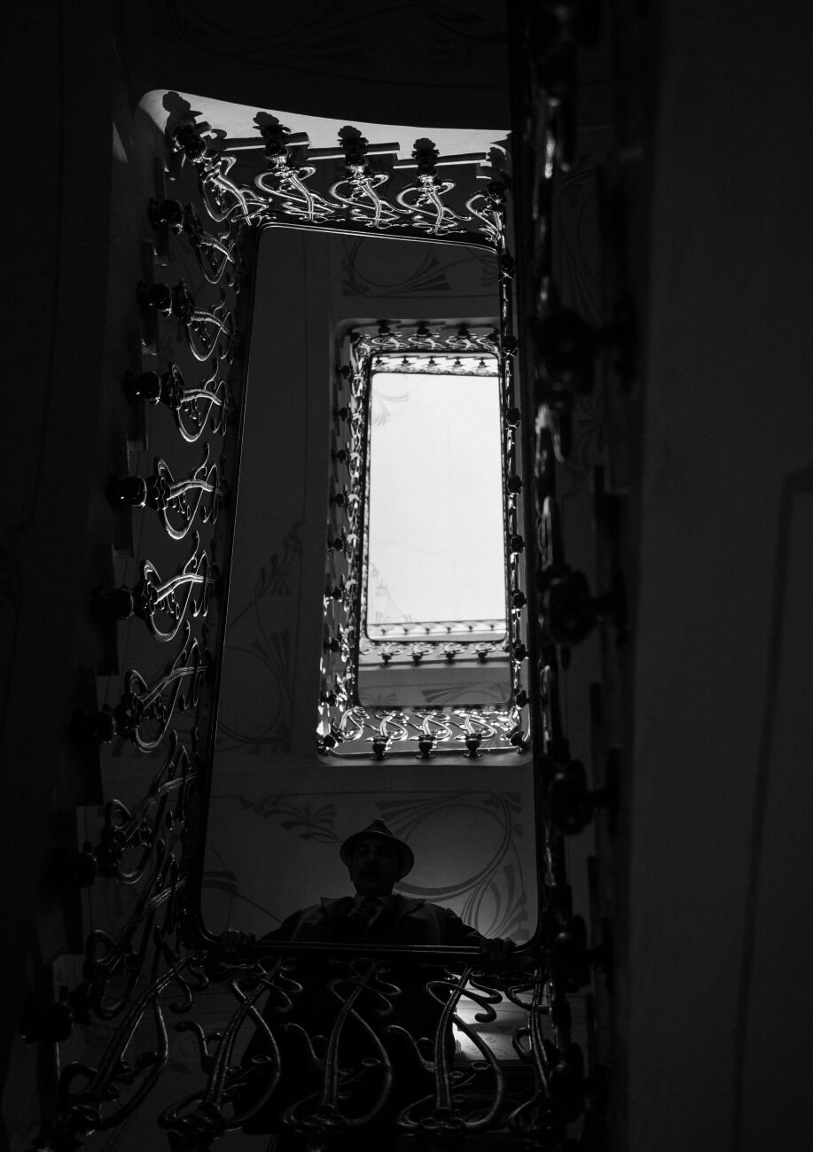 Un hombre se asoma por la escalera de un edificio antiguo y mira hacia abajo