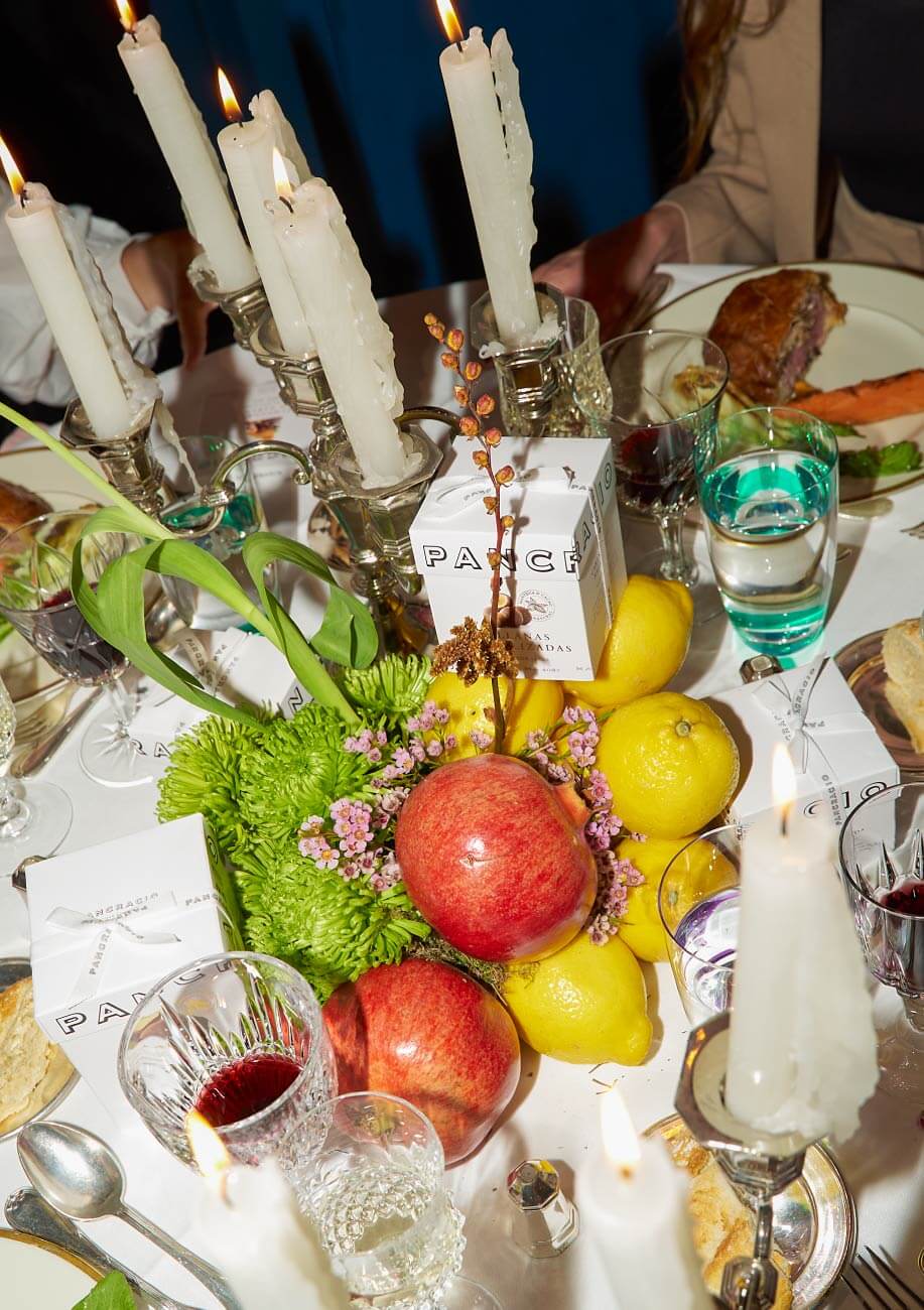 Bodegón de manzanas, limones, flores y velas en el centro de la mesa de comer